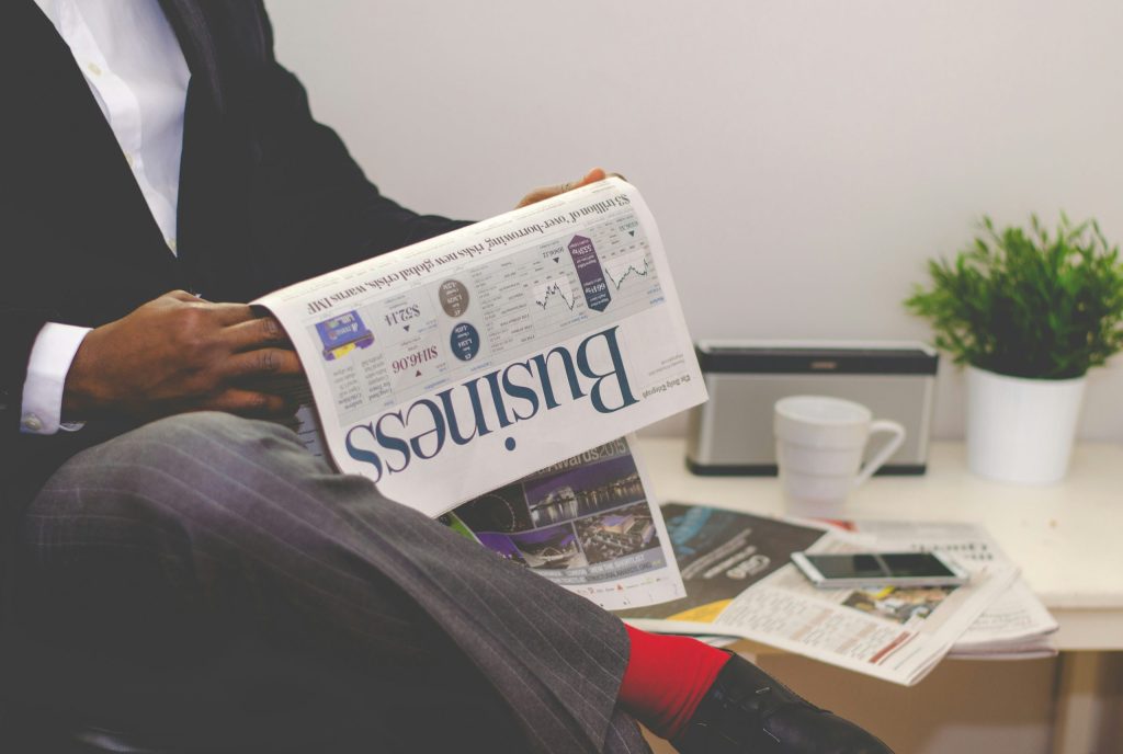 Homem elegante lendo jornal de assuntos do mercado financeiro.