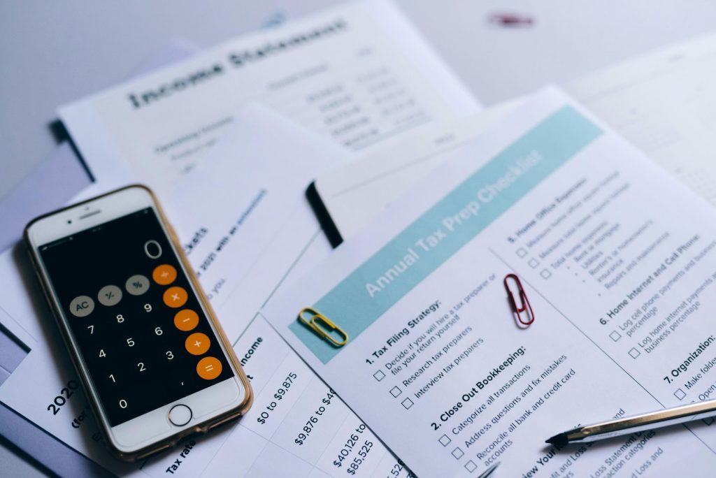 Imagem de documentos financeiros com um smartphone e uma calculadora usada para planejamento tributário anual.